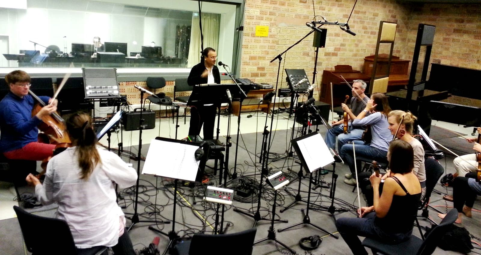 Waheed Alkhan directing a string ensemble during a recording session in a Berlin studio